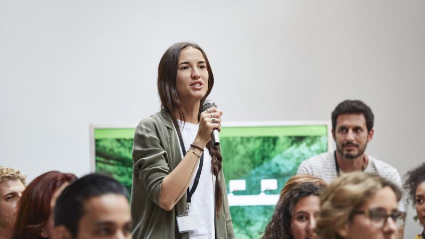 jeune femme prenant la parole dans le cadre d'une réunion publique